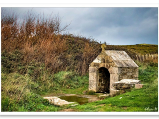 Ancien lavoir en granit au milieu de la lande, entouré d&#039;ajonc et surmonté d&#039;une croix