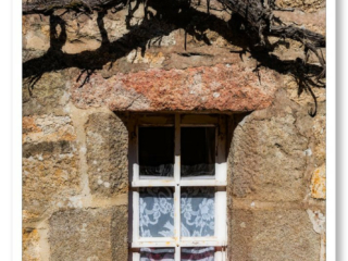 Fenêtre en granit dans une maison traditionnelle bretonne entourée de fleurs