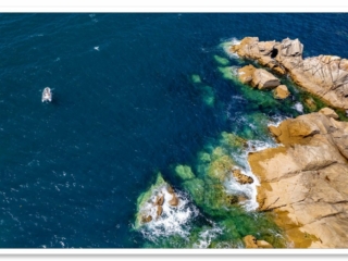 Pêcheur de bar dans son embarcation vue du ciel près des rochers