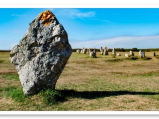 Imposant menhir à Camaret-sur-Mer sous un ciel azur, drapé de lichen doré