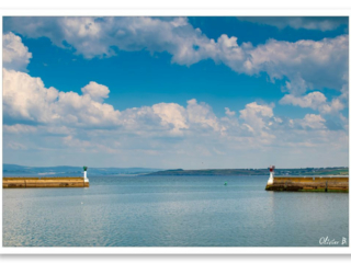 Entrée du port de pêche de Douarnenez sous un ciel cotonneux, mettant en valeur les deux digues