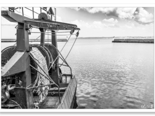 Un chalutier amarré au port de pêche de Douarnenez sous un ciel aux nuages capricieux