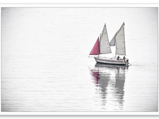 Navire de plaisance avançant paisiblement sur une mer calme sous des voiles et un foc rouge, image minimaliste