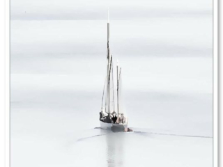 Un voilier évoque un songe, glissant doucement sur les douces vagues, son reflet s&#039;étirant à l&#039;horizon