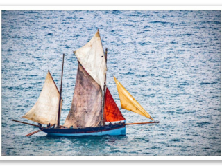 Un vieux chalutier aux voiles multicolores, tel un arc-en-ciel en mer